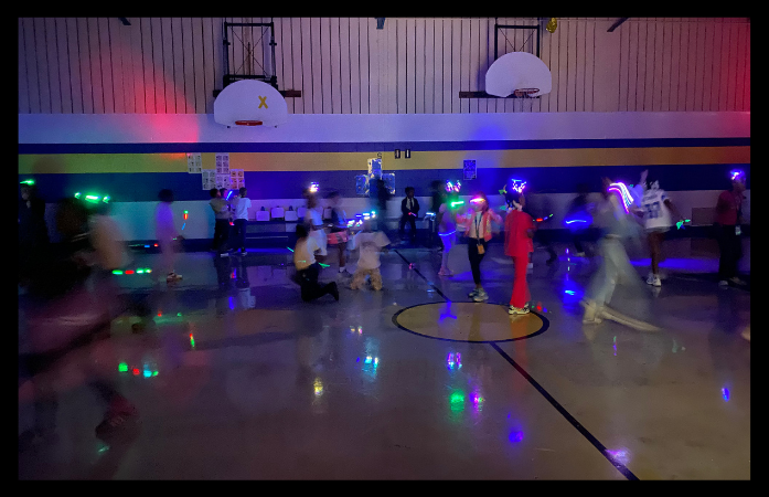  students dancing in the gym with glow accessories